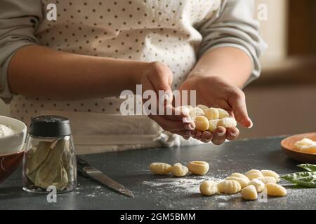 Woman holding tasty gnocchi at table in kitchen, closeup Stock Photo
