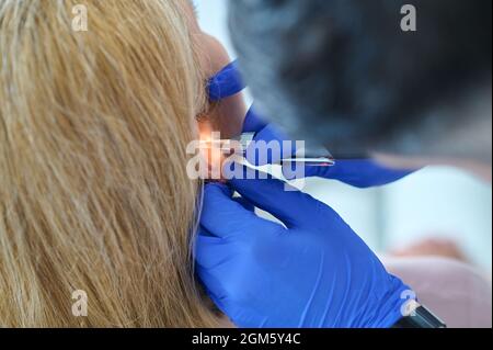 Doctor with gloves examining patients ear Stock Photo