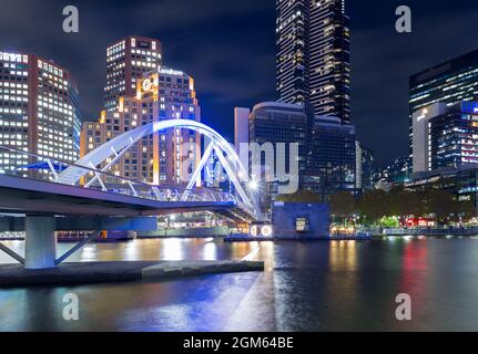 A night view of Melbourne, Australia, seen from the Yarra River at the Evan Walker Bridge, looking towards Southbank highrise buildings.