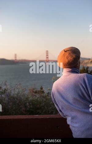 A woman leans on a railing enjoying a view of the Golden Gate Bridge. Stock Photo