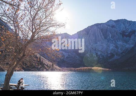 Lone person enjoys solitude in Majestic alpine lake landscape at sunset Stock Photo
