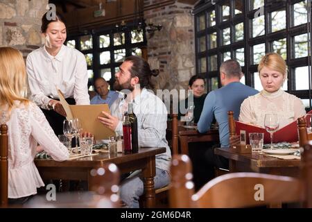 Guests of the country restaurant discuss menu with waitress Stock Photo