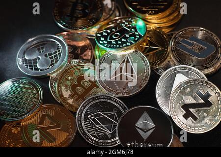 A lot of cryptocurrency coins lie on a dark surface background. View of cryptocurrency tokens, Bitcoin, Ethereum, Zcash, OES, and Dash saw from above on a black background. High quality photo Stock Photo