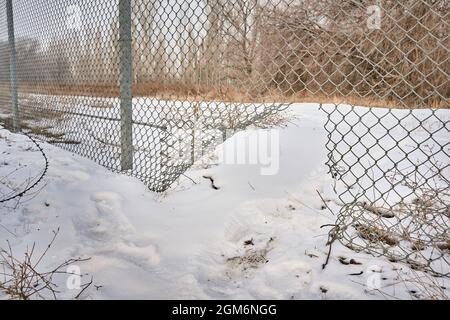 Hole in wire border fence. Illegal trespassing. Escape from prison or closed institution for mentally ill. Maximum security detention facility. Stock Photo