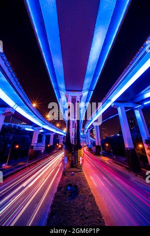 Abstract cityscape traffic with motion blur. Moving through modern city street with neon illuminated bridges. Stock Photo