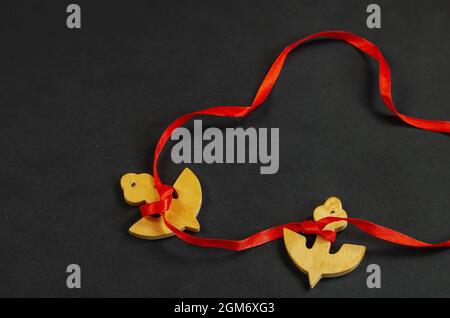 Two wooden anchors tied with red ribbon. Anchor figures on black Stock Photo