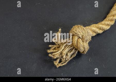 Jute rope with a knot on a black background. Twisted rope is mad Stock Photo