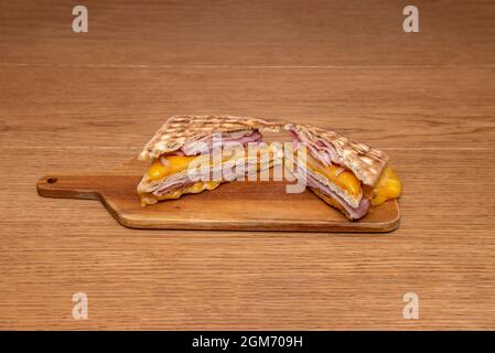 melted cheese and york ham sandwich with grilled panini bread on wooden board Stock Photo