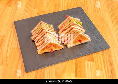 club sandwich skewered with layers of chicken fillet, ham and cheese in tranchetes, lettuce and tomato, mayonnaise and mustard Stock Photo