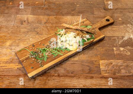 Chicken sandwich with slices of village bread with peas and pumpkin seeds with arugula and hollandaise cream on wooden board Stock Photo