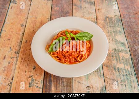 Plate of spaghetti with lots of bolognese sauce and minced beef topped with basil leaves on white plate Stock Photo