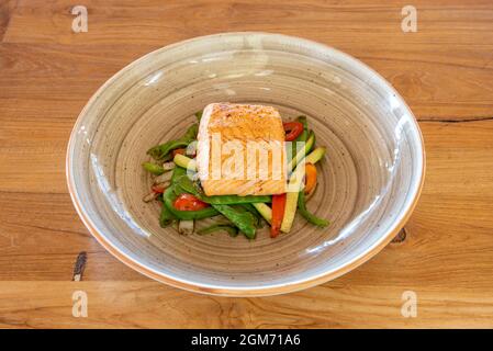 Delicious grilled salmon taco on a bed of veggies in a gray deep plate Stock Photo