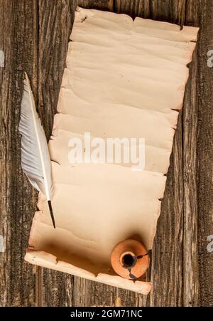 scroll of paper with place for text pen for writing and inkwell on rough wooden table Stock Photo