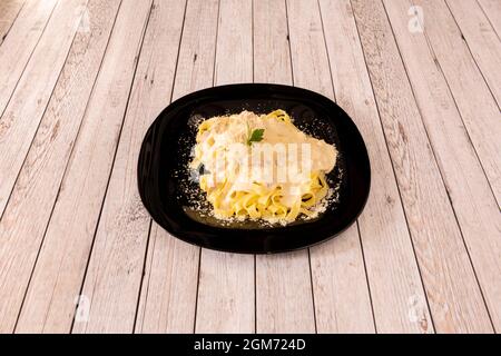 Tagliatelle made with fresh pasta, with carbonara sauce with guanciale on wooden table Stock Photo