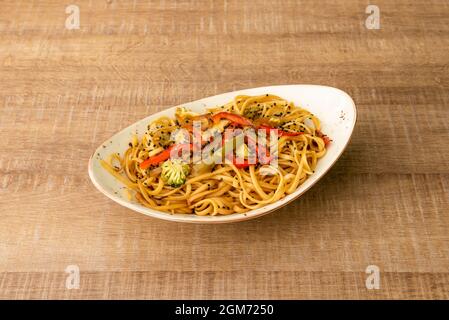 Chunky noodles sauteed with vegetables and broccoli with lots of soy sauce and poppy seeds cooked by a Chinese chef Stock Photo
