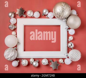 White frame surrounded with silver and white Christmas decorations on pink background mockup Stock Photo