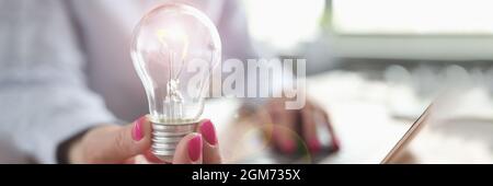 Woman typing on laptop keyboard and light bulb in hand closeup Stock Photo