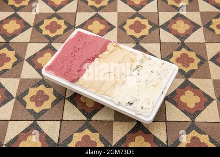 Delicious three-flavored half-liter ice cream tub on hydraulic tile table Stock Photo