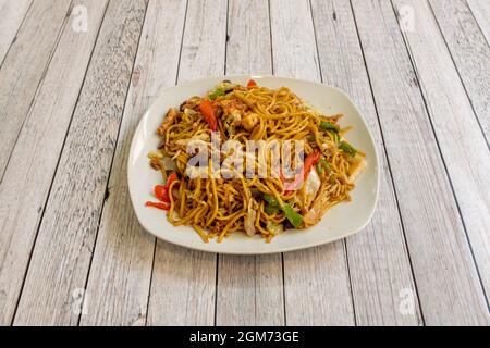 Chinese fine noodles sauteed with vegetables three delicacies and soy sauce with green and red peppers, fried egg and carrot Stock Photo
