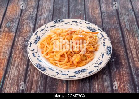 Plate of udon noodles sauteed with shrimp, onion and vegetables made in a Chinese restaurant. Stock Photo