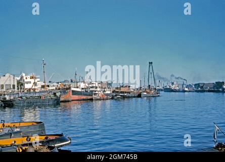 A view of dock activity on the waterfront at the docks district of La Boca, Buenos Aires, Argentina in 1961. The boats are mostly smaller craft, with larger vessels in the background right. As one of the capital’s 48 ‘barrios’ (neighbourhoods), La Boca is located in the city's south-east. It retains a strong Italian flavour, with many of its early settlers being from the city of Genoa. This image is from an old amateur 35mm Kodak colour transparency – a vintage 1960s photograph. Stock Photo