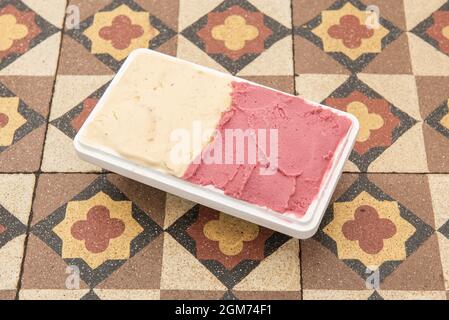 Half-liter tub of ice cream with two flavors in a home delivery container on hydraulic tiles Stock Photo