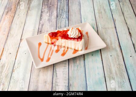 Portion of cheesecake with strawberry jam with a touch of cream and strawberry syrup on a white plate Stock Photo