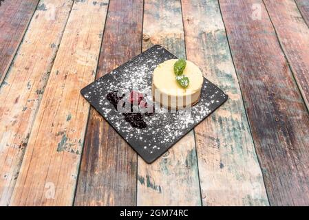 Individual cheesecake with berries, blueberry jam, mint leaves and powdered sugar. Stock Photo