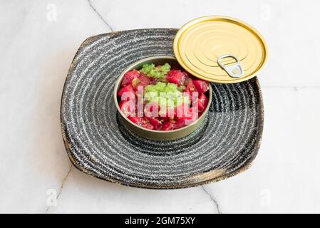 Red tuna tartare with green fish roe presented in a container similar to canned fish Stock Photo