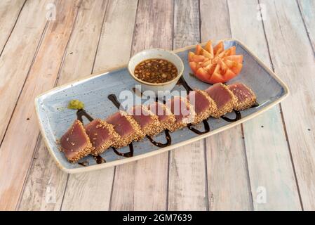 Delicious red tuna tataki with seed and sauce to dip on a blue plate Stock Photo