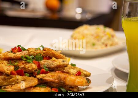 Plate of fried shrimp in tempura with chopped vegetables on table in Chinese restaurant. Stock Photo