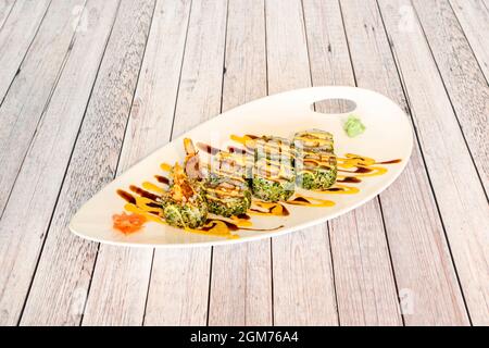 Japanese Uramaki fried in tempura with prawns, seaweed, soy sauce, ginseng and wasabi Stock Photo