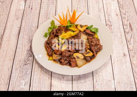 Chinese popular recipe of chopped beef stewed with oyster sauce with mushrooms, bamboo and onions with parsley and coriander on white plate Stock Photo