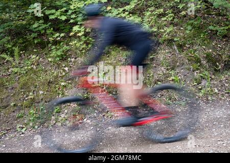 Blurred image of a man on mountain bike on dusty road during MTB cycling competition in Sigulda, Gauja National Park, Latvia Stock Photo
