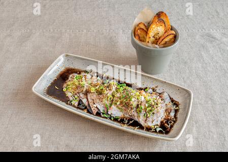 Spanish recipe for raw sea bass tiradito with soy sauce and toast bread Stock Photo