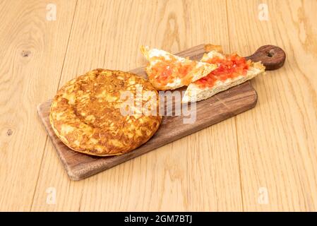 Spanish omelette to share for breakfast with tumaca bread on a wooden table in a Spanish tapas bar Stock Photo