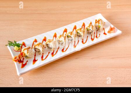 Sushi uramaki dragon roll stuffed with shrimp in tempura, ripe avocado and nori seaweed with soy sauce Stock Photo