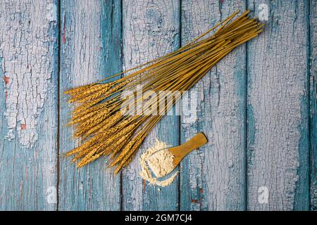 bunch of dried wheat stalks used for decorative motifs and wooden spoon with processed wheat flour Stock Photo