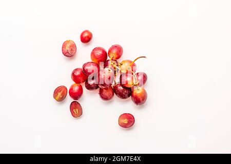 Small bunch of ripe dessert grapes on white background, some split in half Stock Photo
