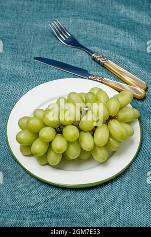 Plate of white dessert grapes on enameled metal plate with vintage cutlery Stock Photo