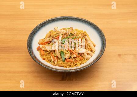 Yakisoba noodles sauteed with carrots, zucchini and chicken strips with poppy seeds and sesame with chives Stock Photo