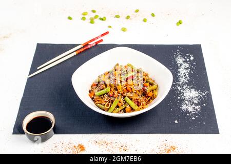 Sauteed noodles with vegetables, sesame and poppy seeds, coarse salt and yakisoba sauce with chopstic Stock Photo