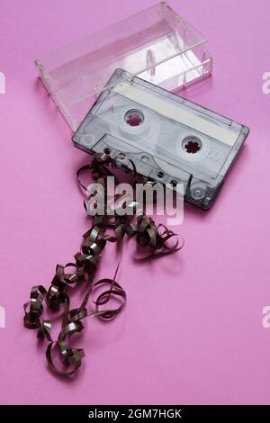 cassette with ribbon rolled up outside on pink background Stock Photo