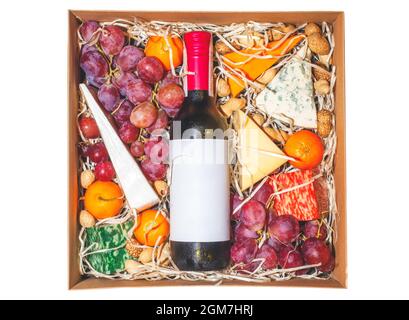 Cardboard gift box with wine bottle and fruit isolated on white background. Present box with cheese, grapes, tangerines, and red wine cut out. Gourmet Stock Photo