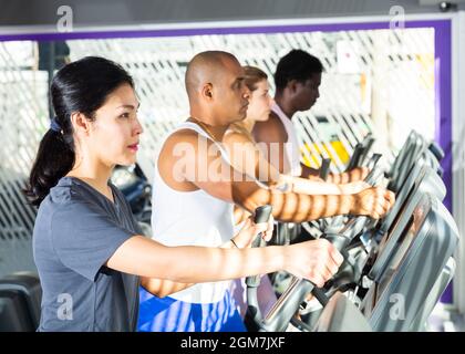 People having running elliptical trainer class in club Stock Photo