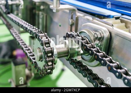 Gear and chain drive shaft in conveyor chain, and conveyor belt is on production line. Stock Photo