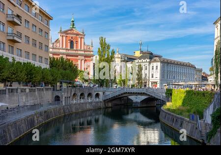 Preseren Square with Tromostovje bridge on Ljubljanica river in Slovenia Ljubjana with Cerkev Marijinega oznanjenja church with river bank Stock Photo