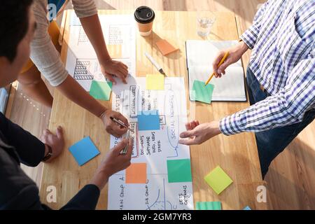 Group of business people discussing big project and writing main thoughts and ideas on colorful sticky notes Stock Photo