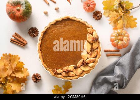 Homemade tasty pumpkin pie with autumn decorations and leaves for Thanksgiving Day on white background. View from above. Flat lay. Stock Photo