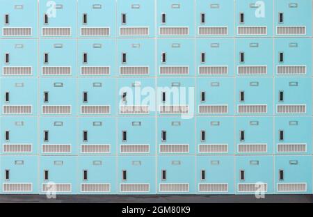 A front on view of a stack of Spring green metal school lockers with combination locks and doors shut as background Stock Photo